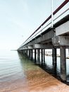 Perspective scenery of concrete road bridge crossing vast calm river with blue water on clear summer day