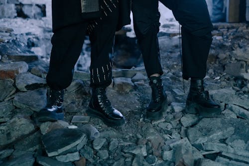 灰色のコンクリートの床に立っている黒いズボンと黒い革の靴の人