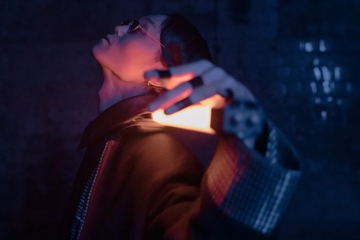 一名男子身穿未来感服装，在霓虹灯下摆出姿势，展现了赛博朋克时尚
