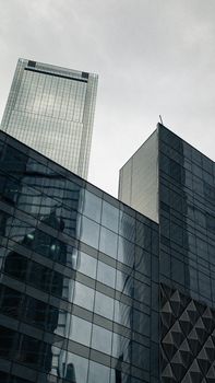 当代摩天大楼低角度视图，其立面采用反光玻璃，位于城市之中