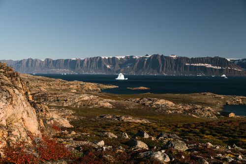 Free A stunning view of icebergs in a serene sea with towering mountains in the distance, capturing the essence of Arctic wilderness. Stock Photo