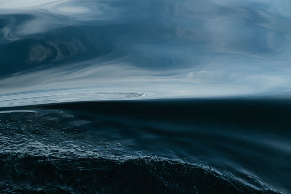 A dramatic abstract depiction of ocean waves under a stormy sky at sunset.