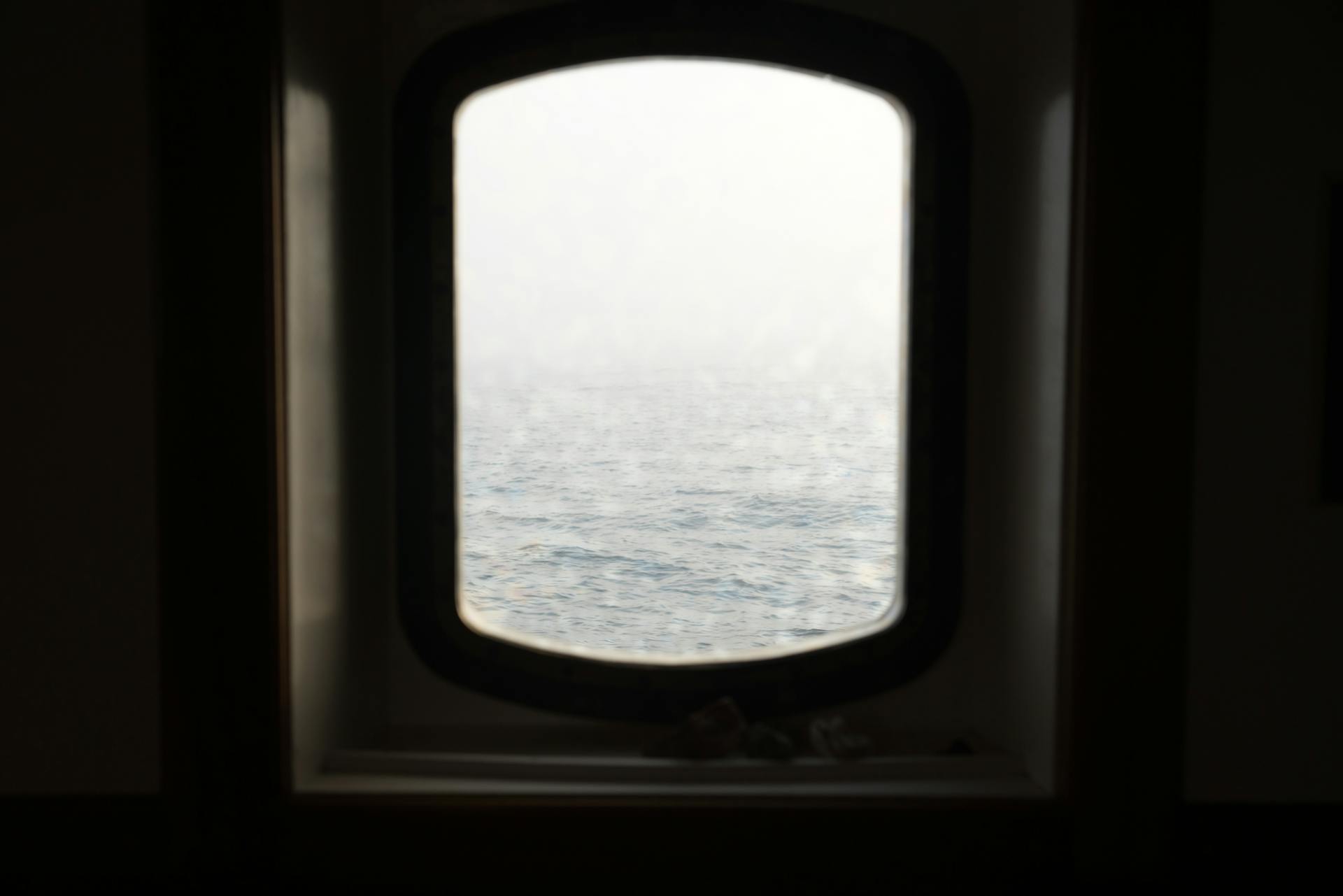 Tranquil view of the ocean through a ship porthole, creating a relaxing maritime scene.