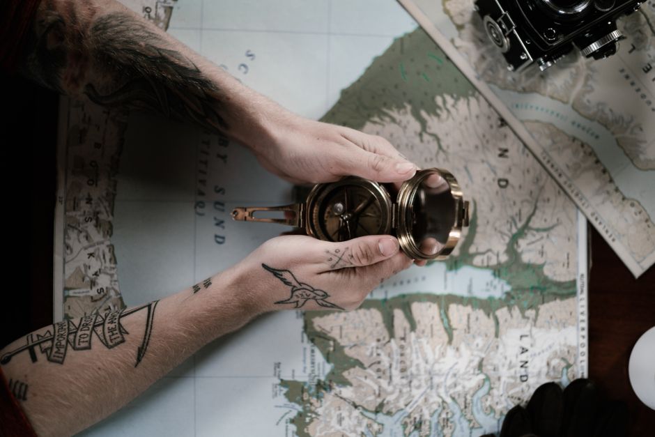 A compass and a map sitting on a wooden desk to represent direction and strategy - Long-term business planning A compass and a map sitting on a wooden desk to represent direction and strategy - Long-term business planning