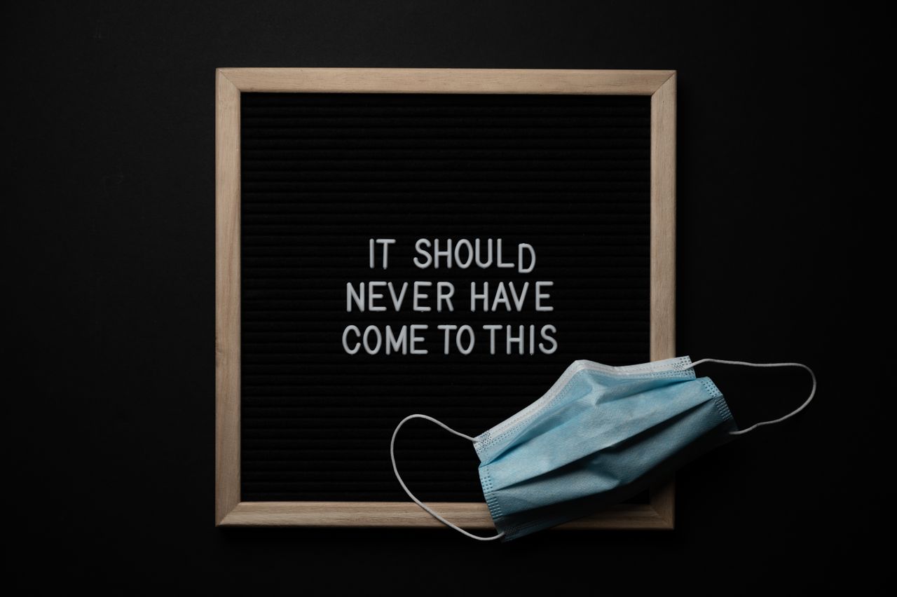 overhead view of medical mask on chalkboard with it should never have