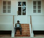 Man in Black Jacket Sitting on Brown Wooden Chair