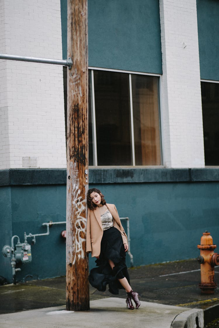 Stylish Pondering Asian Woman Leaning On Post In Town