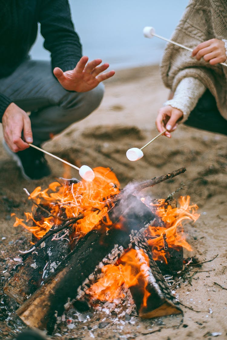 Man And Woman Roasting Marshmallows On Beach