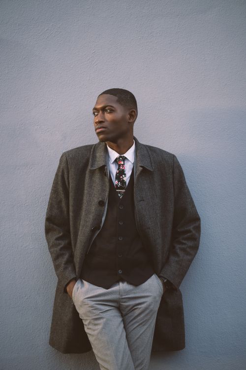 Free Young wistful African American male manager in trendy outfit with hands in pockets looking away on street on gray background Stock Photo
