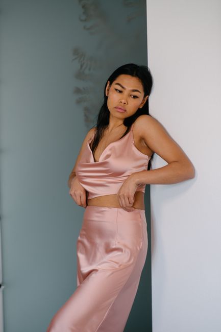 Young upset ethnic female in elegant outfit with makeup looking down near wall