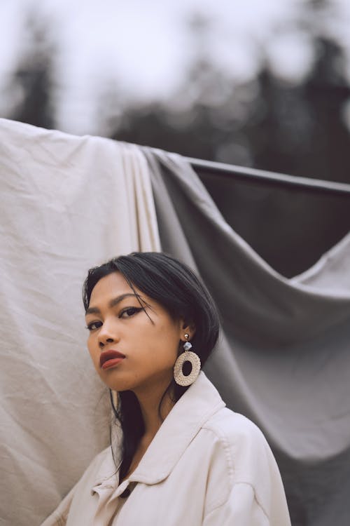 Free Stylish Asian woman in earring near fabrics on street Stock Photo