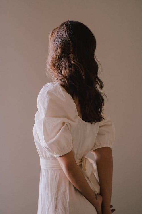 Faceless stylish woman standing with hands behind back