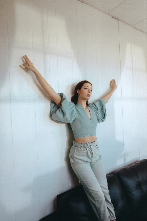 Charming woman leaning on wall and raising arms