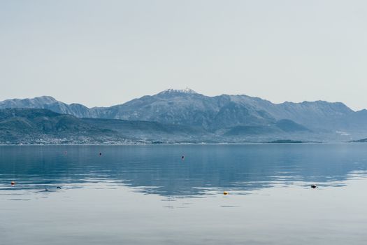 清晨雾气缭绕，宽阔宁静的湖泊风景如画，四周丘陵环绕