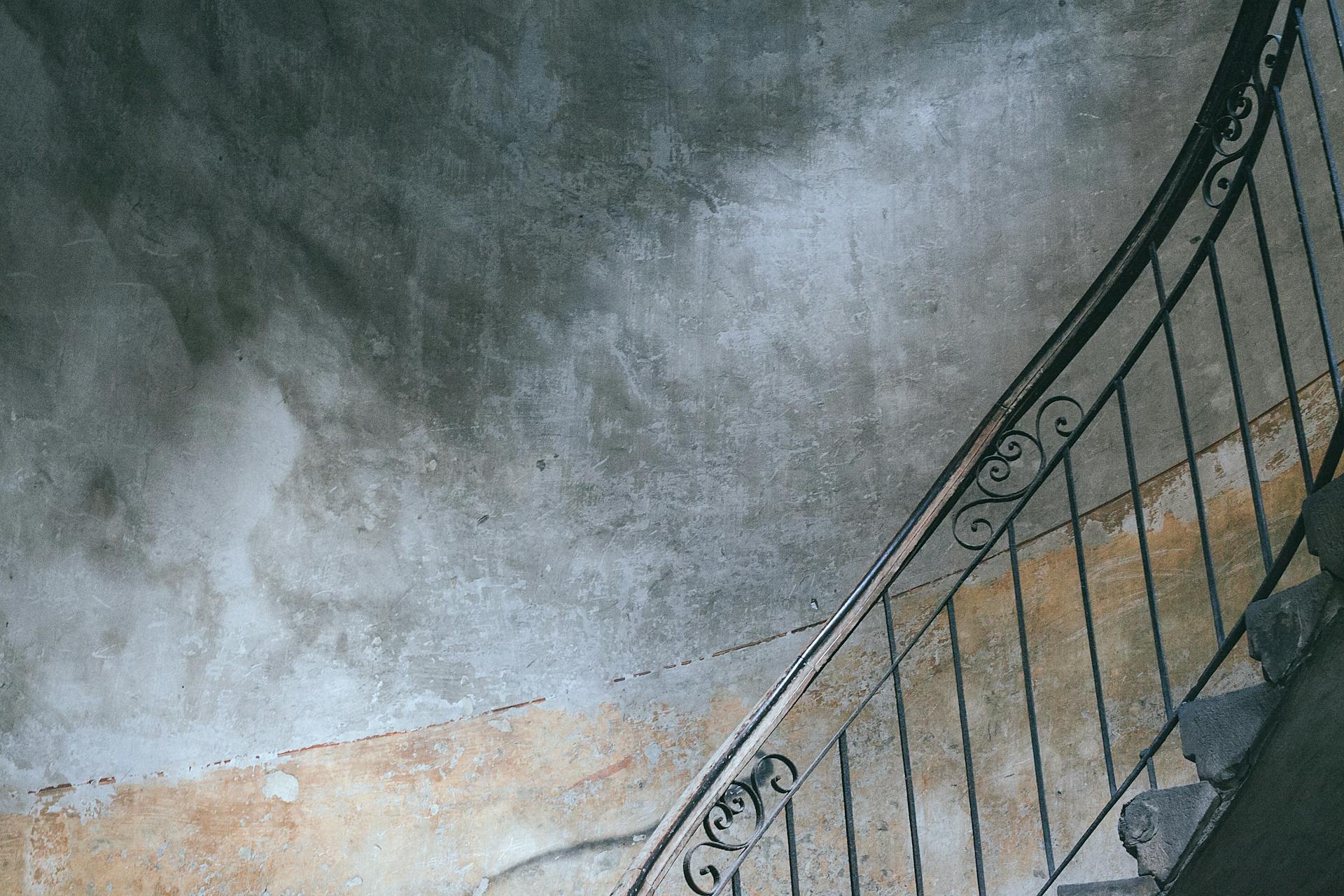 Stairway with metal railings and old shabby walls in porch of dwell building in city