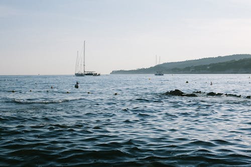 Парусные лодки в волнующемся море возле холмов