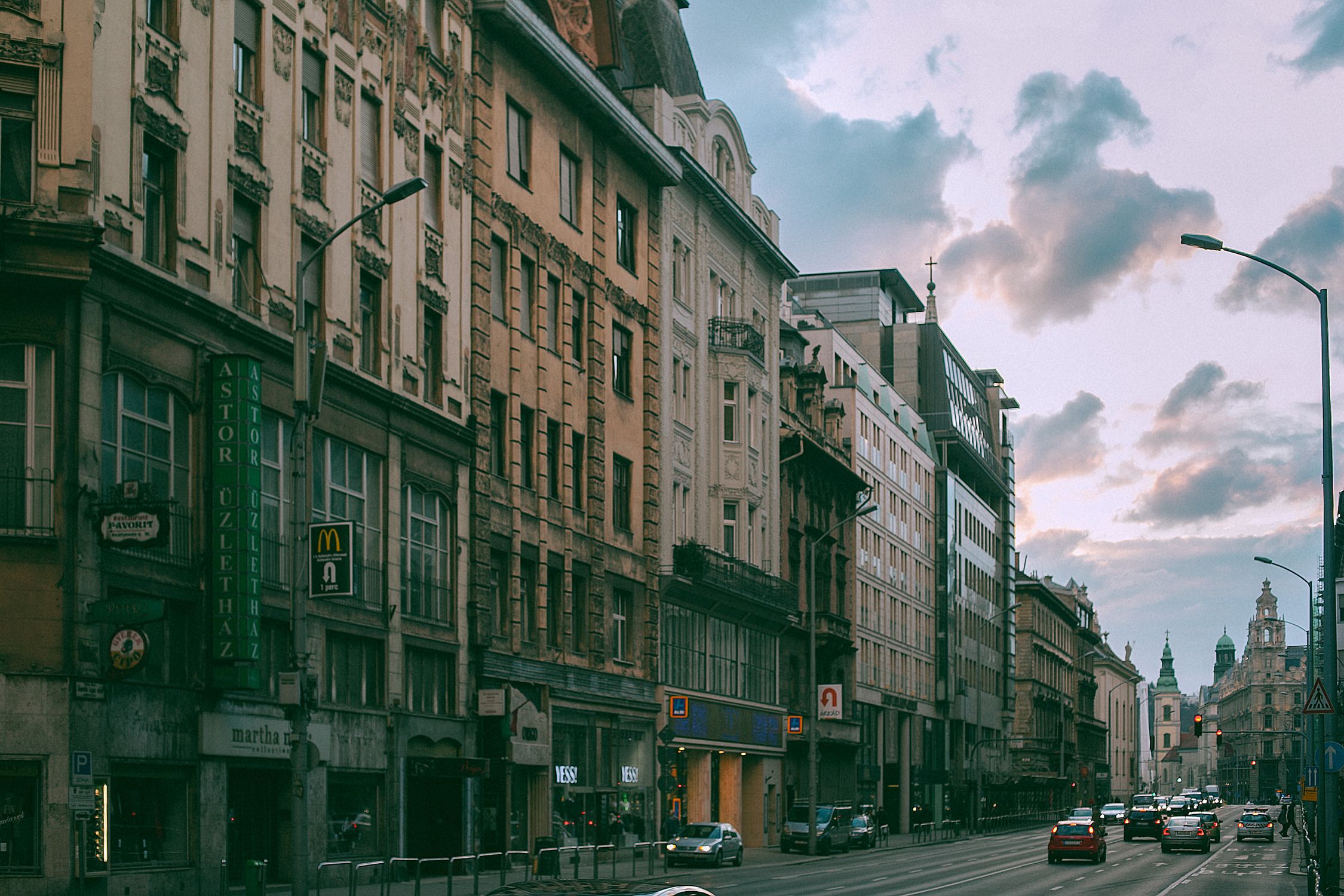 Exterior of structures with classic facades near urban road with transport under cloudy sky