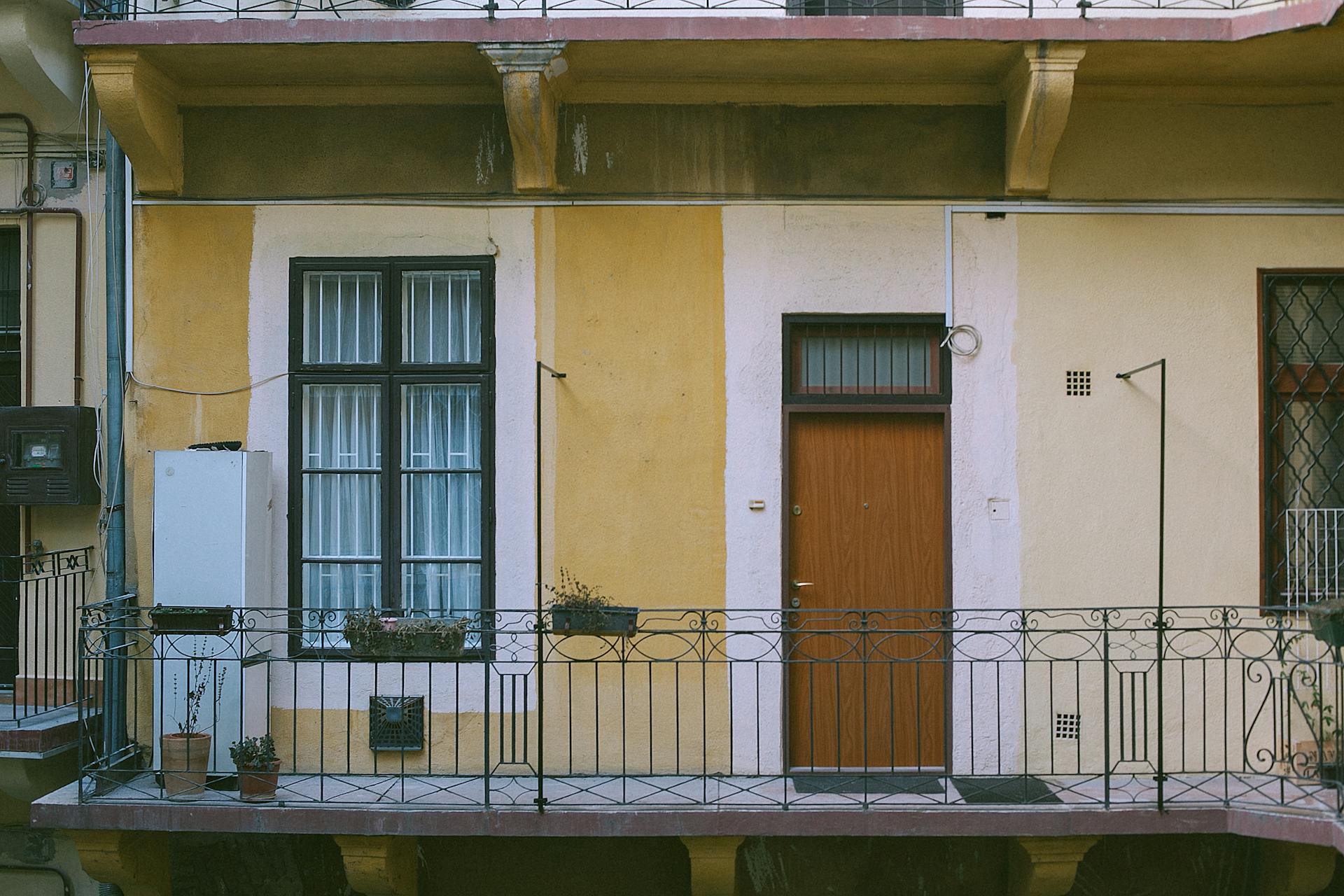 Facade of old dwell building with balcony decorated with potted plants in modern city