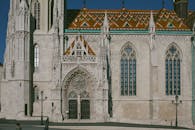 Exterior of Matthias Church with ornamental windows and colorful roof on street in sunny day