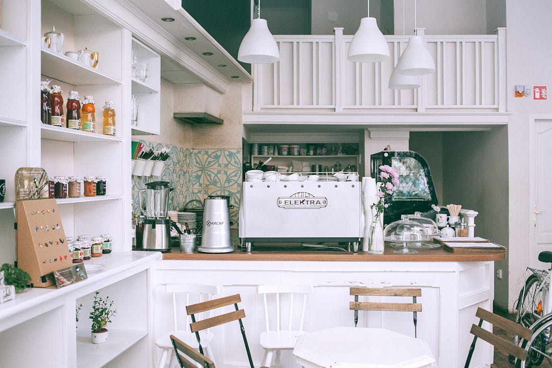 Free White kitchen set with coffee maker and appliances in small cozy coffee shop with flowers and table in daylight Stock Photo