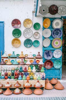 Vibrant ceramic plates and pots displayed in a traditional outdoor market setting.