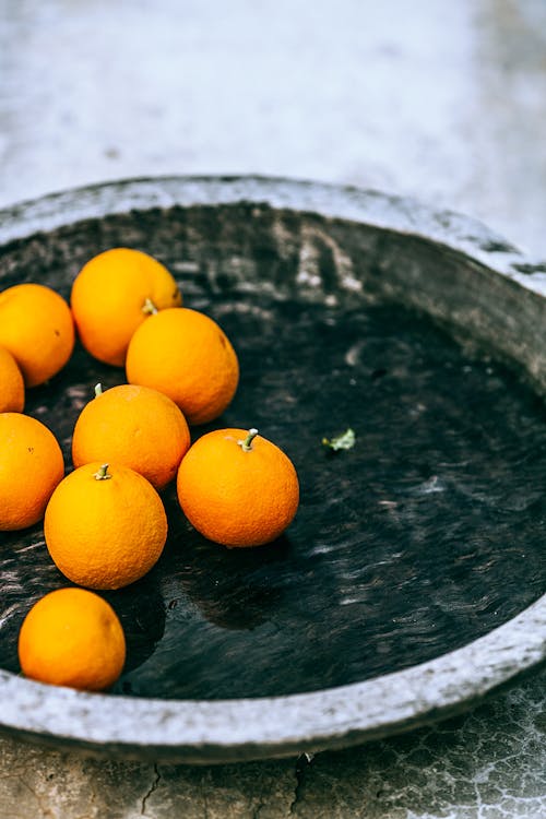 High angle of ripe appetizing tangerines on metal tray on table at home