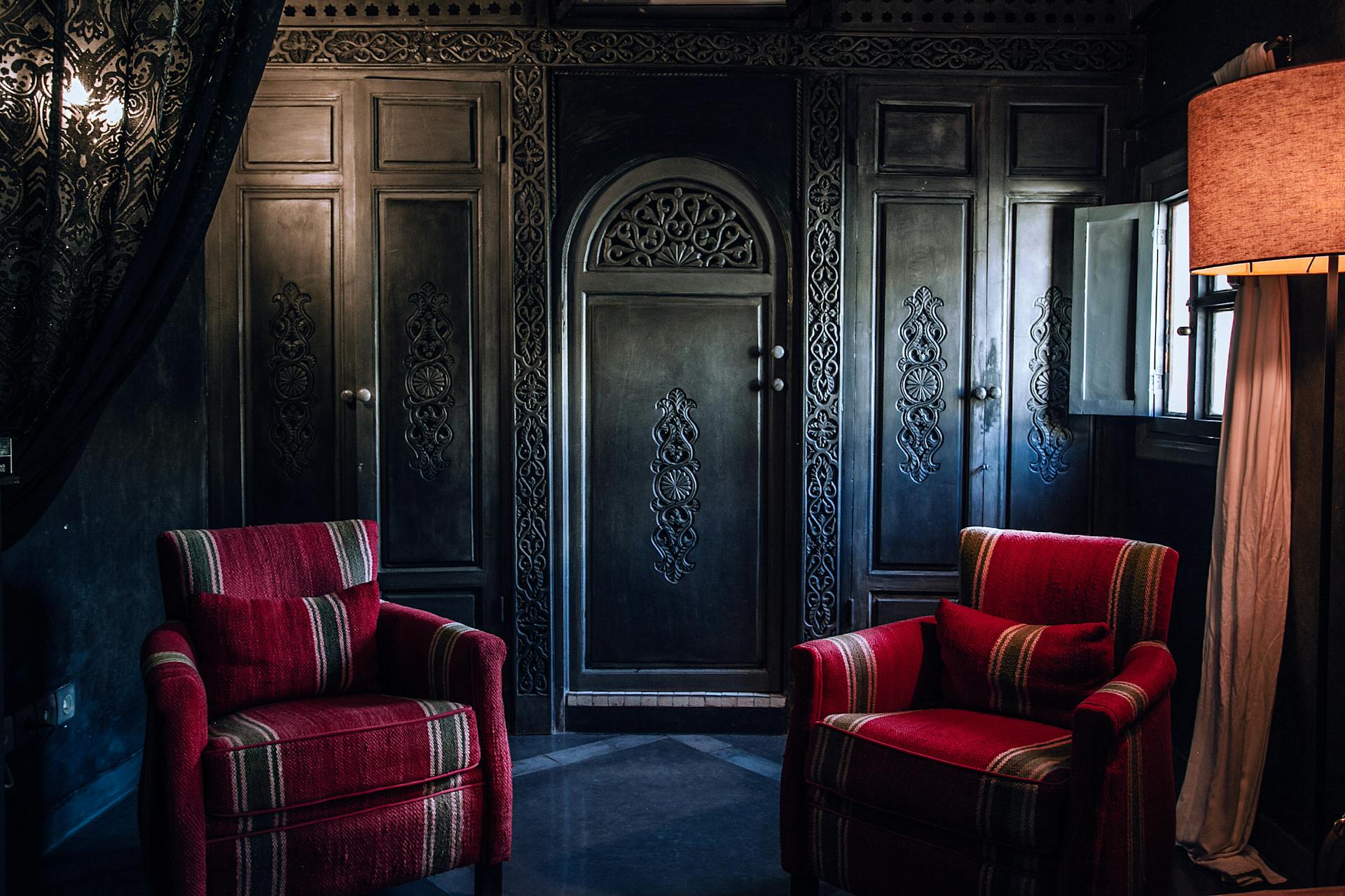 Interior of old fashioned room with ornamental wooden wardrobe and cozy furniture in apartment