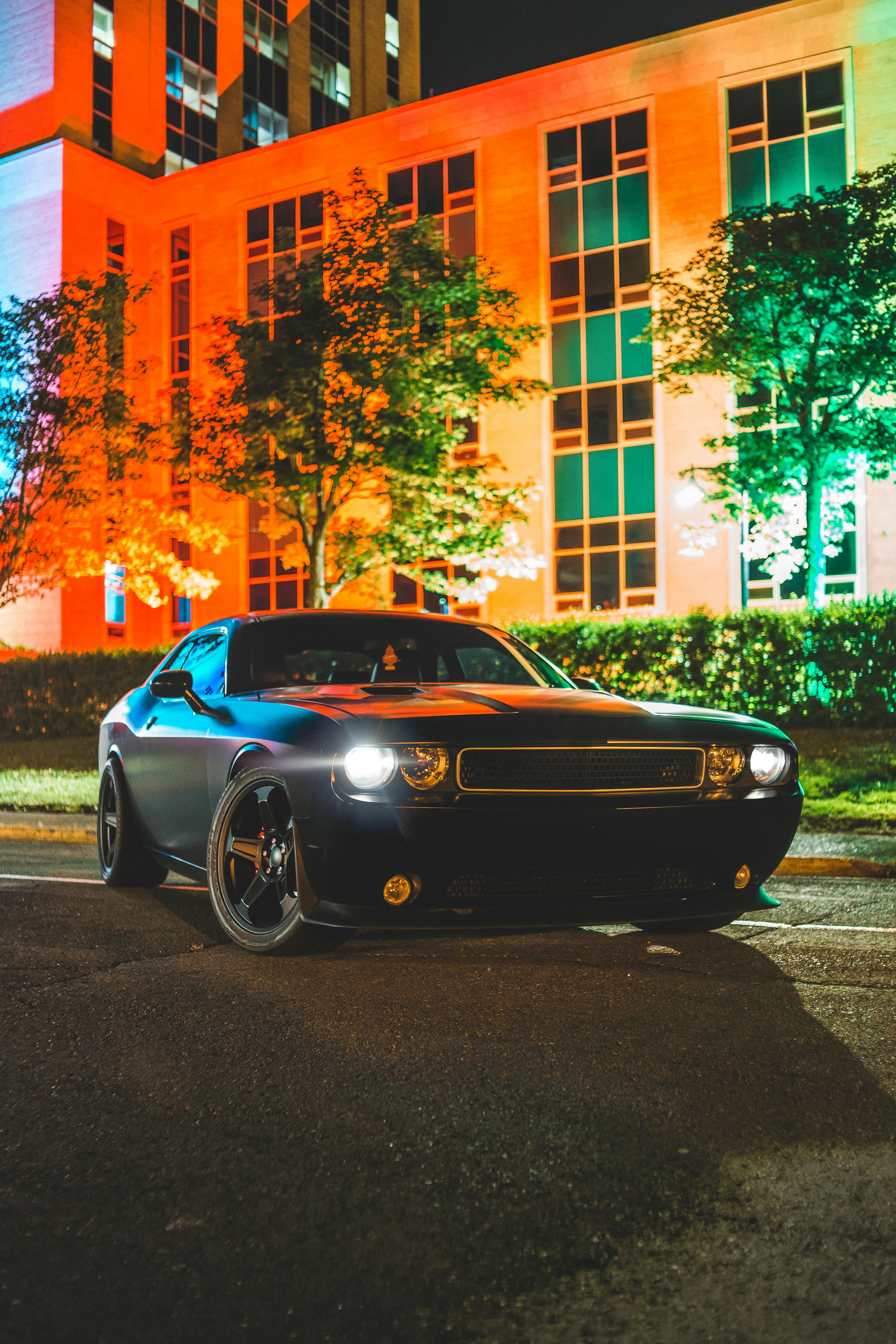 modern car with shining headlights near building