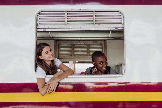 Two women looking out a train window, smiling and enjoying the journey.