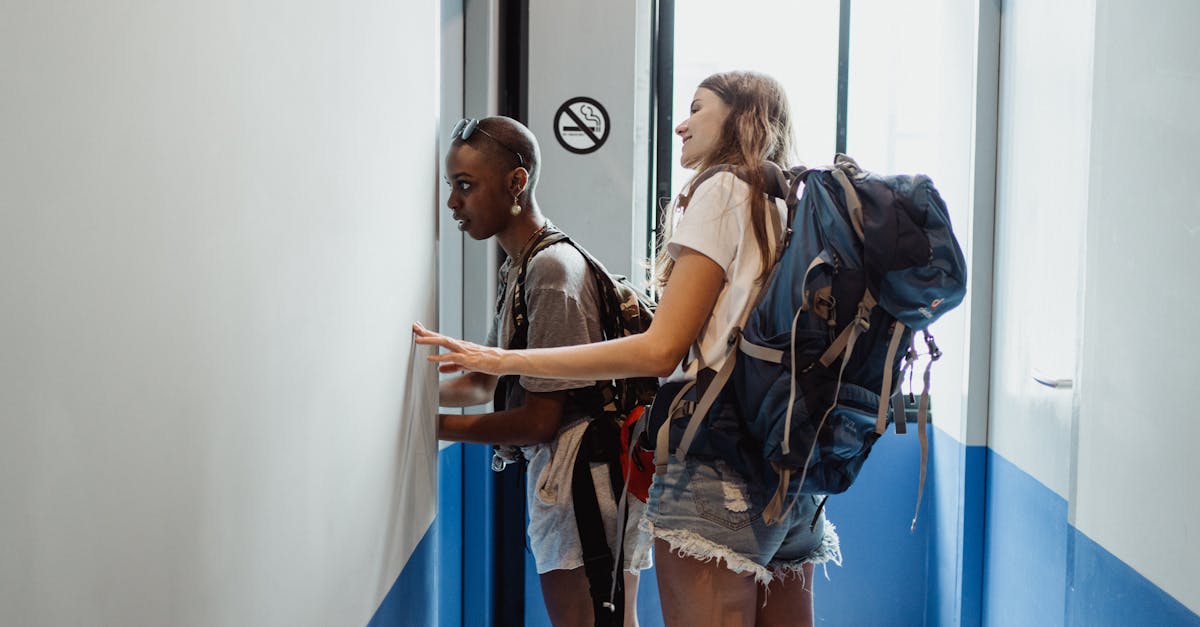 Two women with backpacks entering a hostel room, ready for travel.