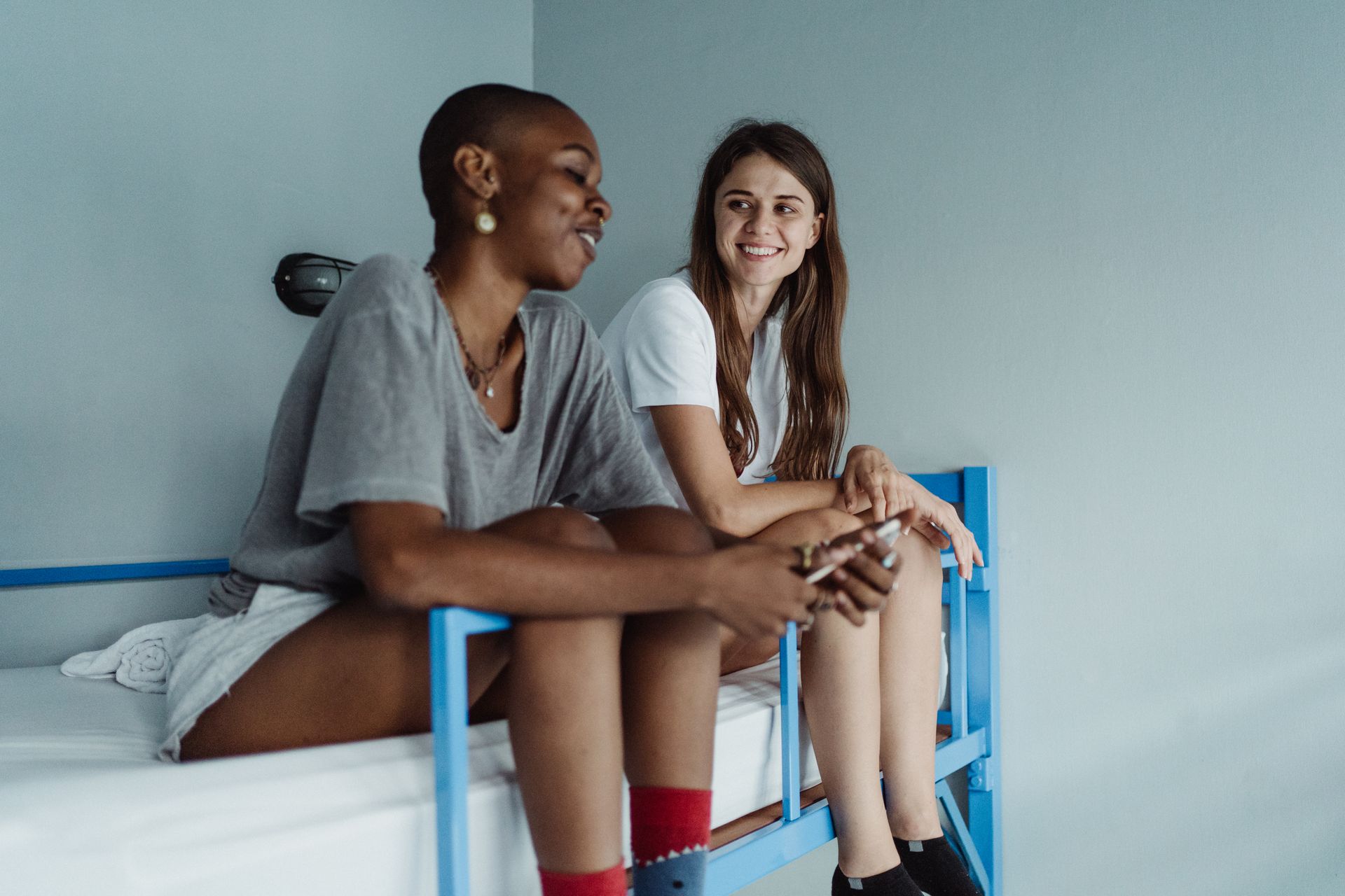 Two Women Sitting on a Bunk Bed and Smiling