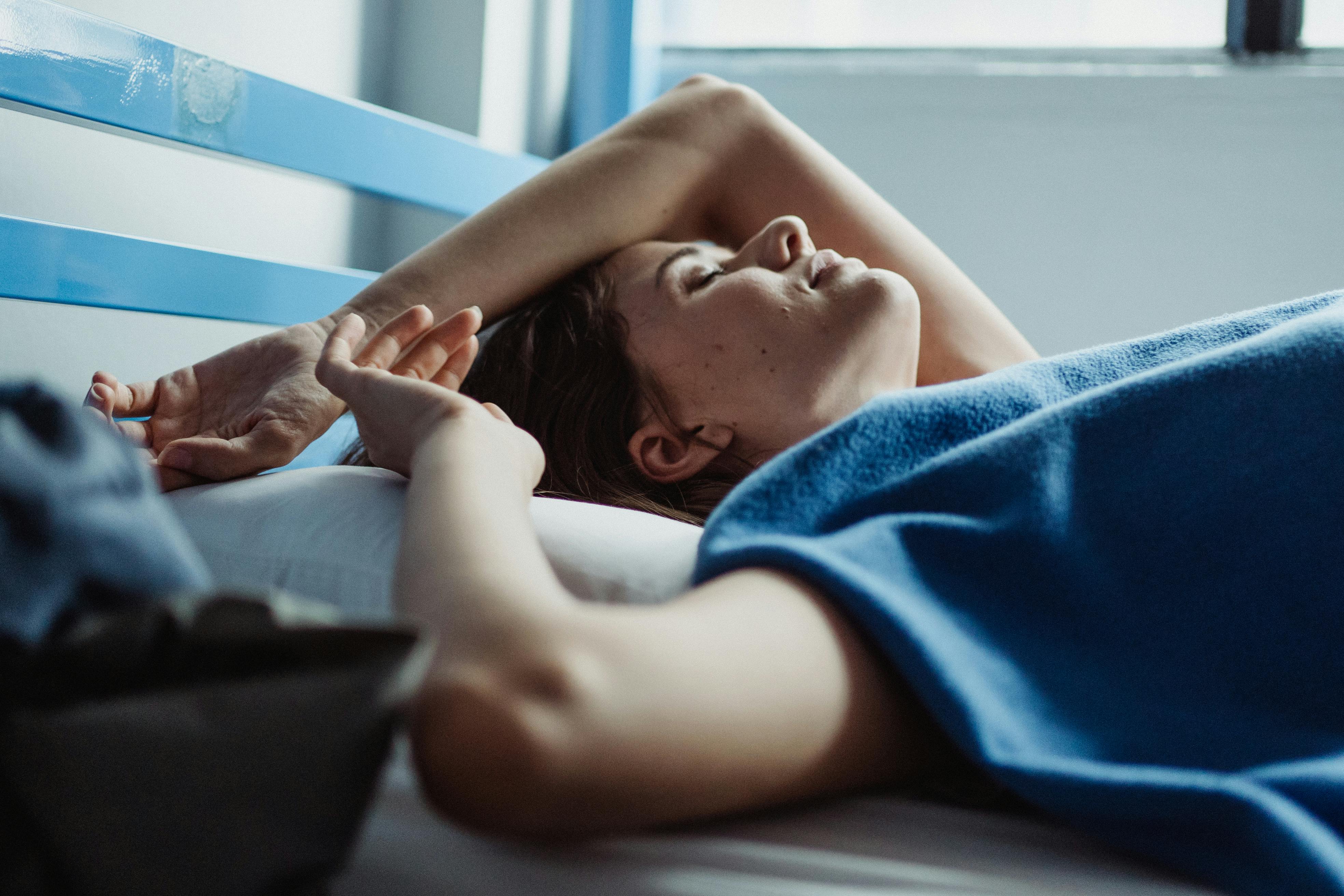 一名女子安详地躺在床上，享受着射进来的柔和晨光