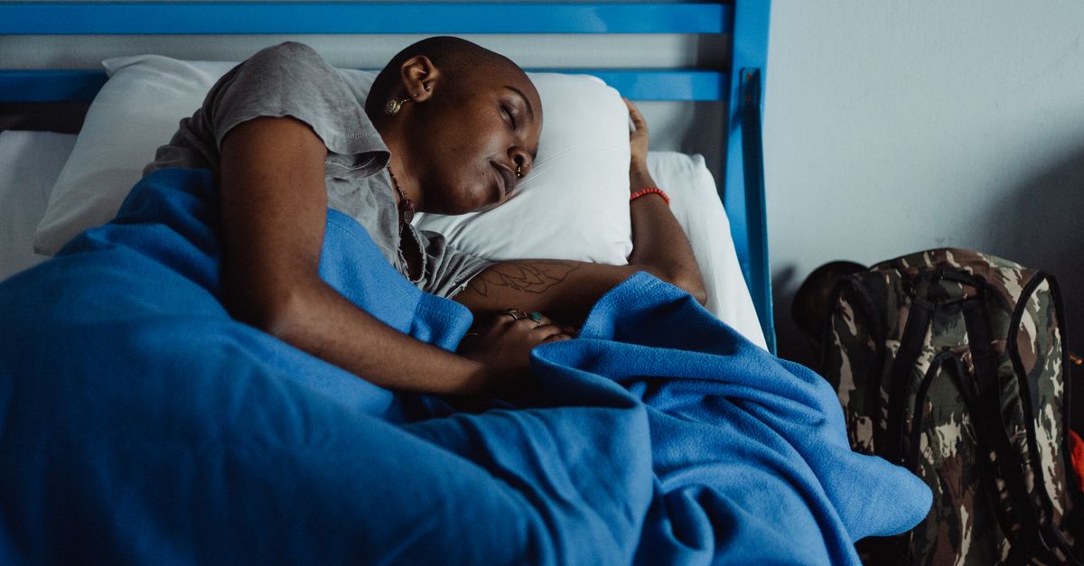 A person sleeping peacefully in a dark room with sunlight streaming through a window