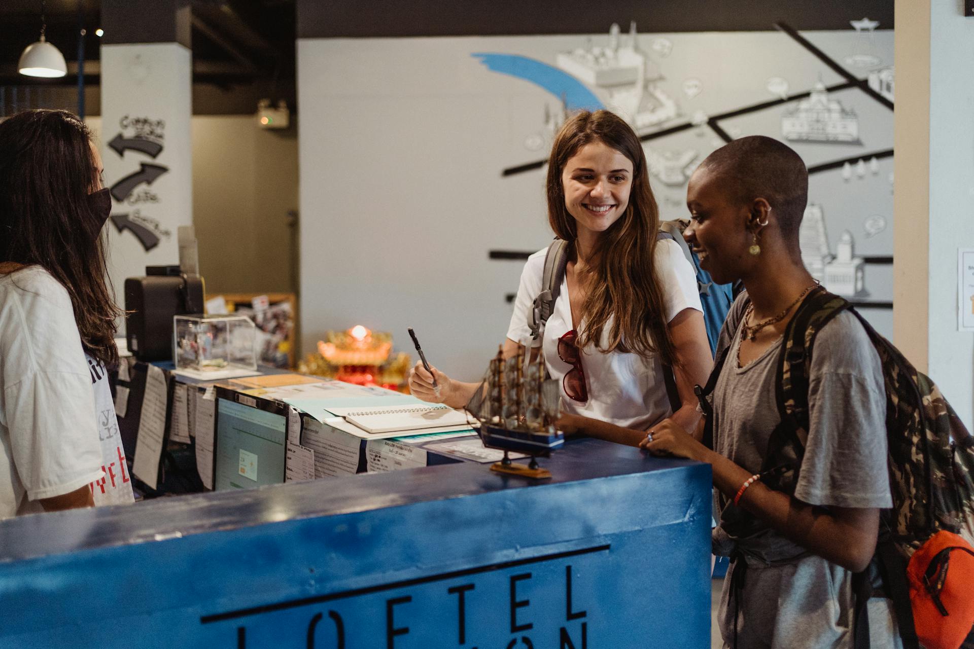 Three travelers checking into a hostel at the reception desk, showcasing hospitality and adventure.