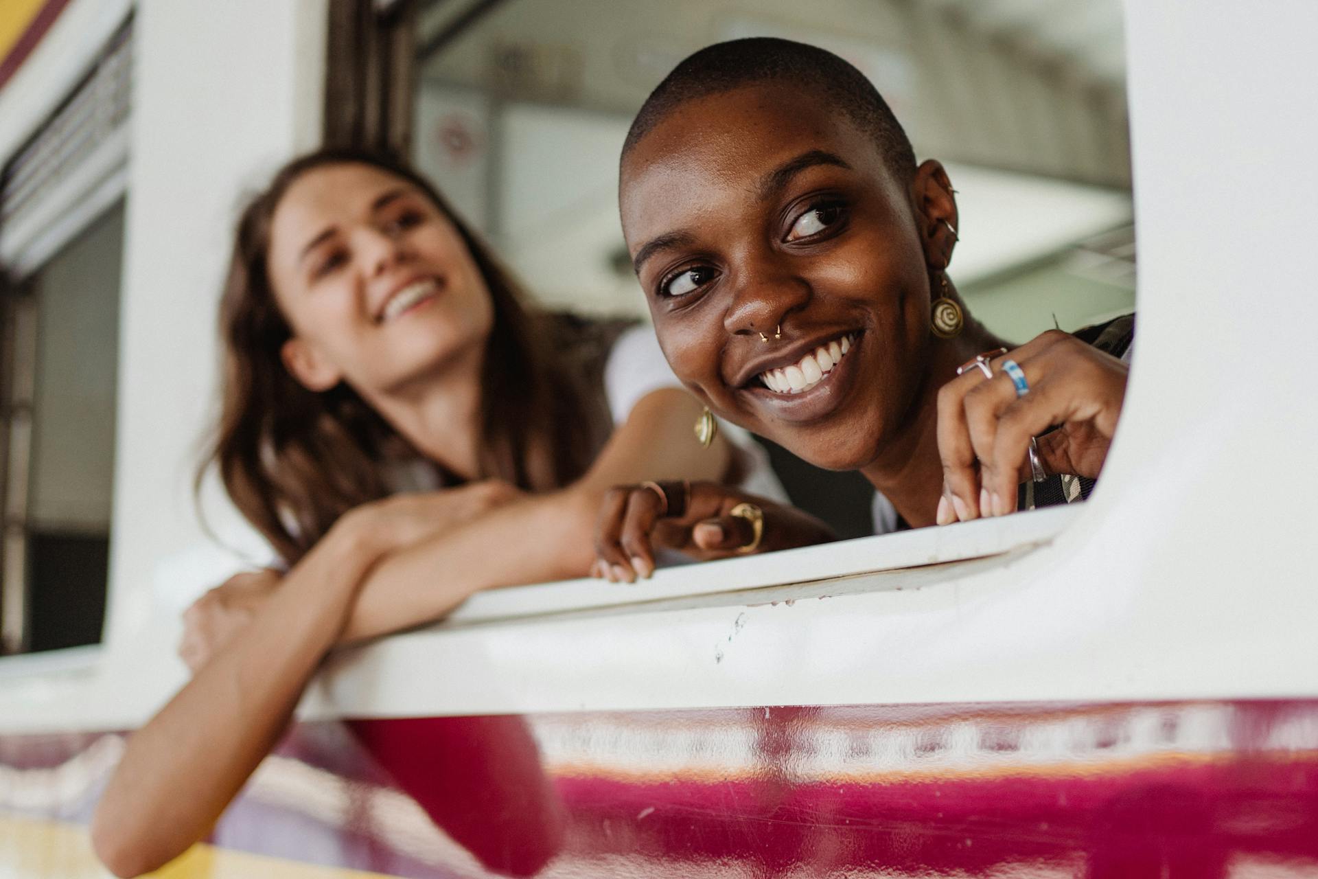 Two women smiling and enjoying a train ride, capturing the essence of travel and friendship.