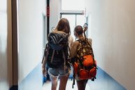 两名女子背着背包走过走廊，暗示着旅行友谊