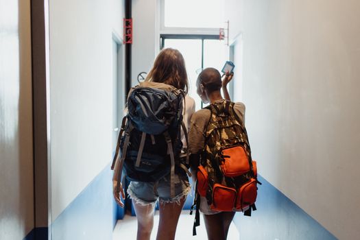 两名女子背着背包走过走廊，暗示着旅行友谊