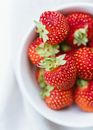 Ripe strawberries in white plate on table