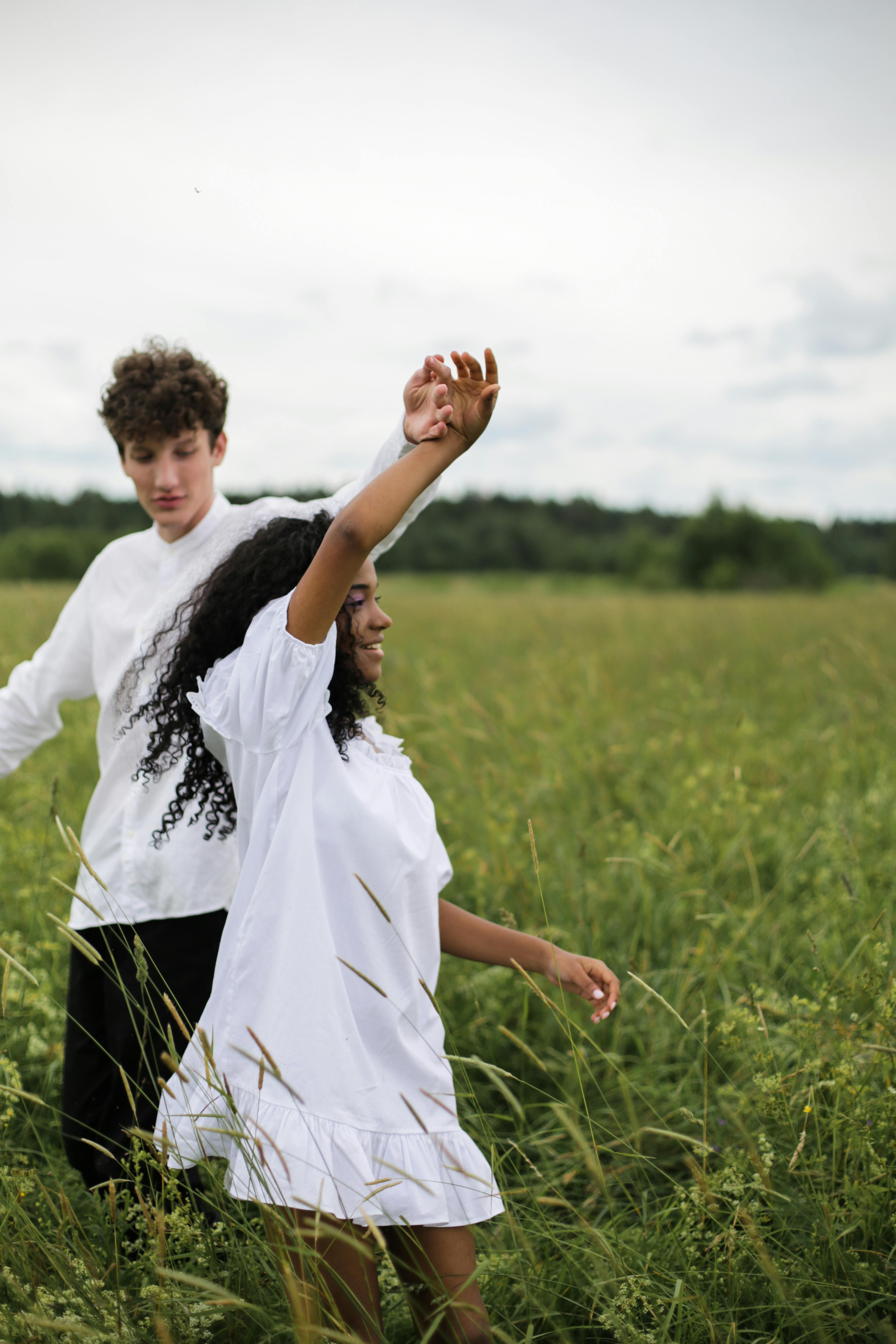 man in white shirt holding woman in white dress on green grass field