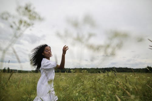 Woman in White Dress Standing on Green Grass Field