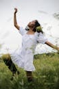夏日郁郁葱葱的草地上，一位身着白色连衣裙的女子正优雅地起舞