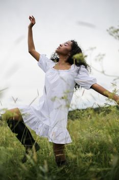 夏日郁郁葱葱的草地上，一位身着白色连衣裙的女子正优雅地起舞