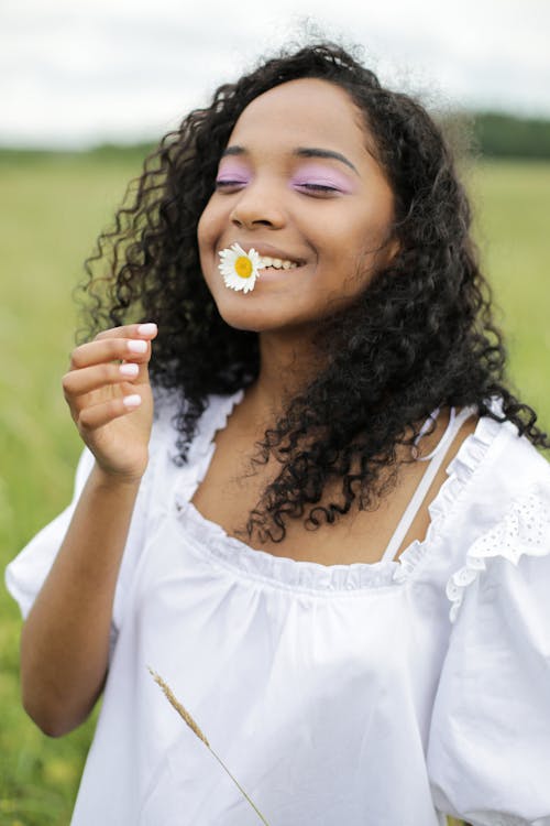 Girl in White Tank Top With Yellow Flower on Her Mouth