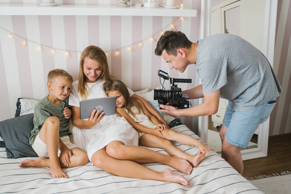 Family enjoying quality time with tablet and camera in a cozy bedroom setting.