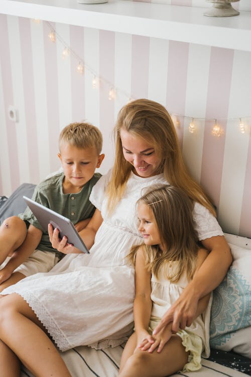 Woman and Kids Looking at the Screen of a Tablet