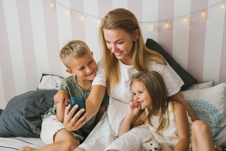 Woman And Her Kids Looking At The Screen Of A Cellphone