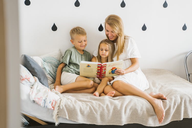 Photograph Of A Mother Reading A Book To Her Children