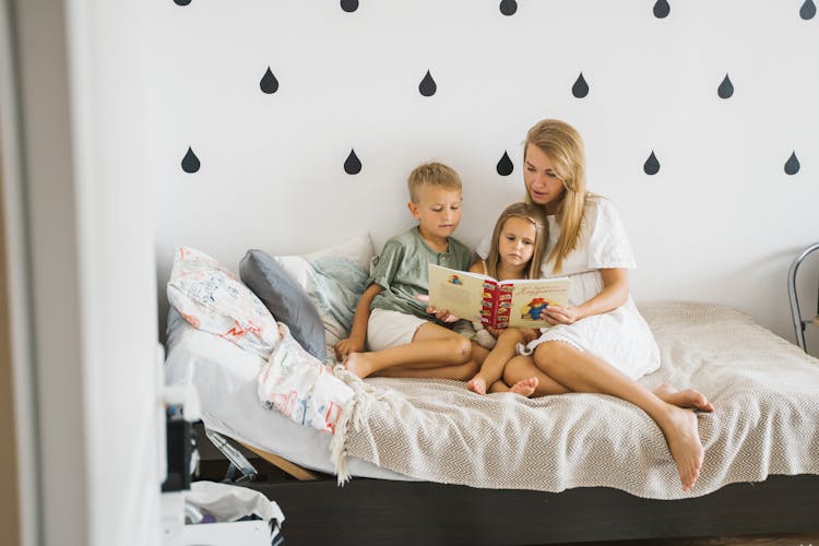 Photo Of A Parent Reading A Book To Her Children