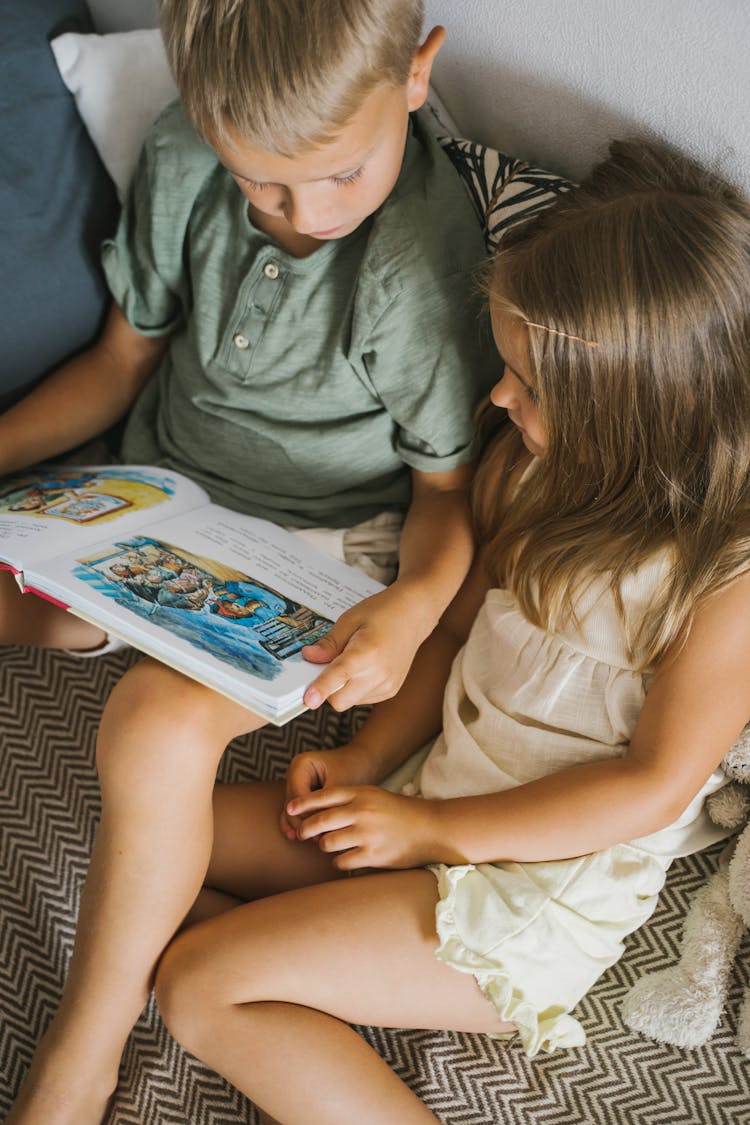 Overhead Shot Of Siblings Reading A Book Together