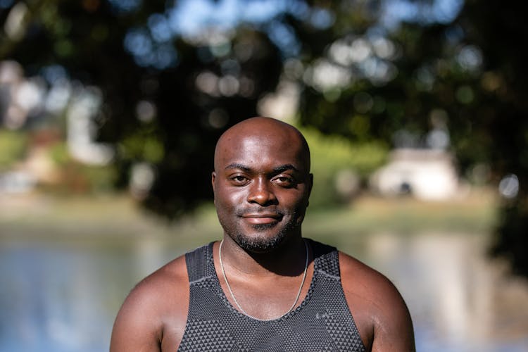 A Bald Man Wearing A Black Tank Top Smiling